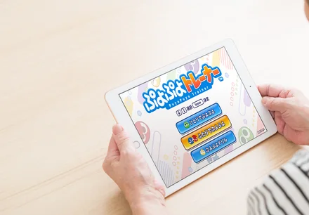 「ぷよぷよトレーナー」のタイトル画面が表示されたタブレットを手にする利用者（利用イメージ）